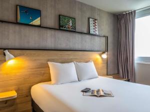 a hotel room with a bed with a book on it at ibis Paris Gennevilliers in Gennevilliers +65 photos