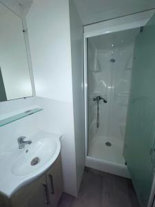 a white bathroom with a sink and a shower at Escale Nature - Bungalow F14 pour 4 au camping Le Ried in Boofzheim +16 photos