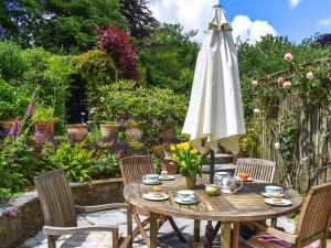 a table with a white umbrella and a table and chairs at Hollyhocks Cottage in Helland
