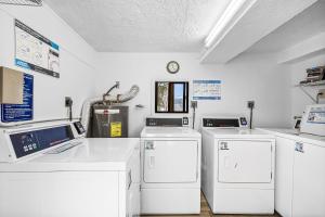 a laundry room with four washes and a clock on the wall at Unwind with Beach Bliss & Sunset Magic - Sunburst 113 in Punta Gorda Beach