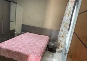 Un dormitorio pequeño con una cama rosa y una cortina. en Residencial Day off, en Guaratuba 8 fotos más