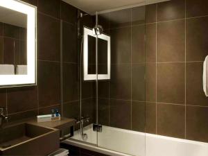 a bathroom with a tub and a sink and a mirror at Novotel Paris Pont De Sevres in Sèvres +72 photos