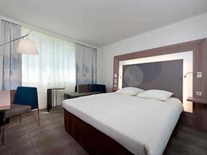 a hotel room with a large bed and a desk at Novotel Paris Pont De Sevres in Sèvres