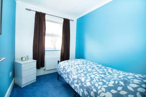 a blue bedroom with a bed and a window at 3 Bed Semi - Sleeps 5 - Wifi - Private Garden & Parking - Pets Allowed in Grove Park