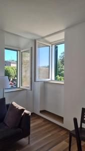 a living room with three windows and a couch at Al Campanile a stylish new apartment San Vito Romano Rome in San Vito Romano