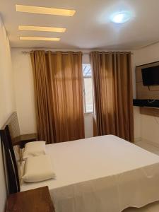 een kamer met een bed, een televisie en gordijnen bij BJLAPA Residence in Bom Jesus da Lapa