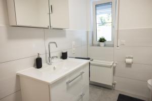 a white bathroom with a sink and a window at Gemütlich wohnen im Herzen des Hunsrücks in Emmelshausen