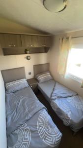 Dos camas en una habitación pequeña con ventana. en 16 orchid meadows, en Ashington