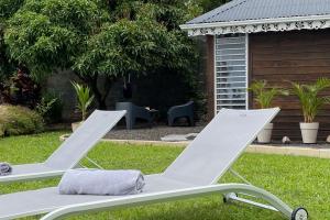 a pair of white lawn chairs in a yard at Villa Le Nid des Colibris in Saint-Charles