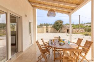 una sala da pranzo con tavolo e sedie su un patio di Villa Incantesimo a Marina di Pescoluse Altre 29 foto
