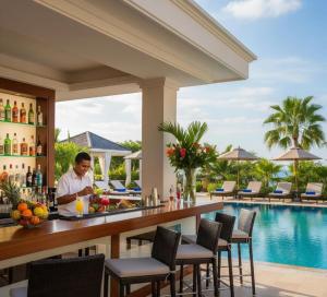 a man standing at a bar at a resort with a swimming pool at Grand Mirage Hotel & Spa in Side