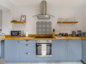 a kitchen with blue cabinets and a stove top oven at Florence Cottage in Heacham +10 photos