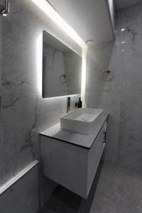 ein weißes Badezimmer mit Waschbecken und Spiegel in der Unterkunft Cozy Loft Monastiraki in Athen