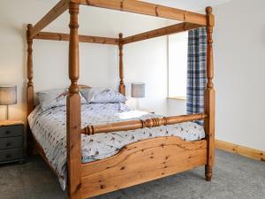 a bedroom with a wooden bed with a wooden frame at West Lanegate Farmhouse in Amisfield Town