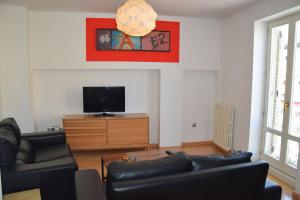 sala de estar con 2 sofás de cuero y TV de pantalla plana en Apartamentos Zaragoza Coso, en Zaragoza