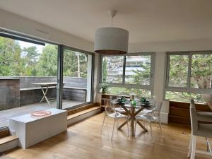 a living room with a table and chairs and windows at Les Terrasses Du Golf in Le Touquet-Paris-Plage