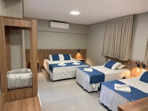 a hotel room with two beds and a chair at Hotel Mato Grosso Inn in Cuiabá
