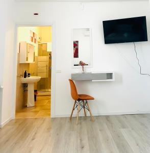 une chaise dans une pièce avec un lavabo et une télévision au mur dans l'établissement crisann house, à Frascati