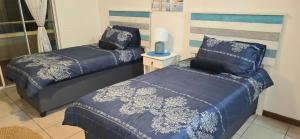 a bedroom with two beds with blue comforters at 102 L'escalier CABANAS-ON THE BEACH in Amanzimtoti +38 photos