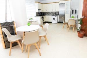 eine Küche mit weißen Tischen und Stühlen und eine Küche mit weißen Geräten in der Unterkunft Apartamento uso Turistico Ancora de Oro 1 in Kap Finisterre