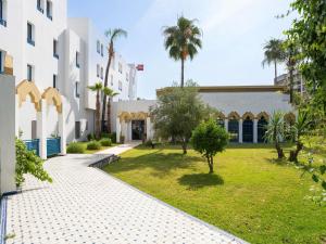 a courtyard of a building with a lawn and palm trees at Ibis Fes in Fès