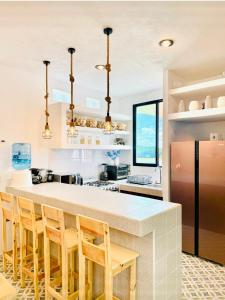 a kitchen with a white counter and wooden chairs at CASA DE PLAYA con PISCINA en SISAL SÚPER EQUIPADA in Sisal