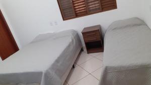 a bedroom with two beds and a night stand at Pousada Am confort turiuba ltda in Turiúba +5 photos