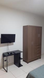 a bedroom with a desk and a wooden cabinet at Pousada Am confort turiuba ltda in Turiúba