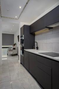 a kitchen with black cabinets and a couch in a room at Edinburgh City 2Bedroom & steam room! in Edinburgh