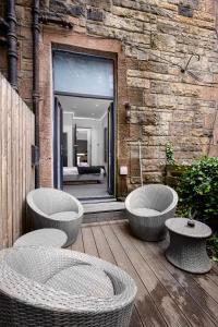 a patio with three wicker chairs and a building at Edinburgh City 2Bedroom & steam room! in Edinburgh