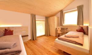 a bedroom with two beds and a desk at Rumlhof Brixen in Bressanone
