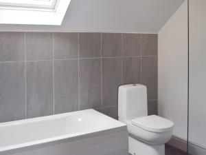 a bathroom with a white toilet and a bath tub at The School House in New Luce