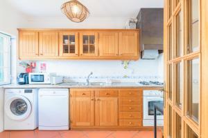 a kitchen with wooden cabinets and a washer and dryer at Casa Margarida in Almograve