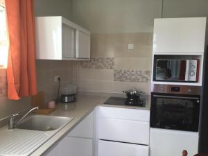 a small kitchen with a sink and a microwave at Villa du coeur in Deshaies +4 photos