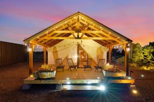 a tent with chairs on a deck at night at Horizon View Wall Tent - Grand Canyon Luxury Camping Retreat in Valle