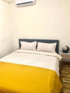 a bed with a yellow and white blanket on it at Charmant T2 a Mtsapere Mamoudzou in Mamoudzou