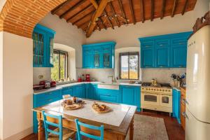 niebieska kuchnia ze stołem i niebieskimi szafkami w obiekcie Villa Posticcia Nuova- Luxury & Privacy in Tuscany w mieście Laterina