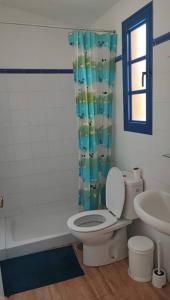 Un baño con inodoro y cortina de ducha. en Ataitana Bungalows Maspalomas, en San Bartolomé