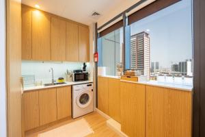 a kitchen with a washing machine and a window at Luxury Studio JVC Open View in Dubai