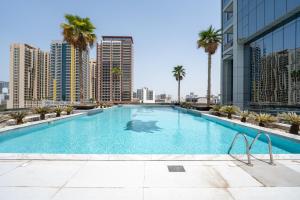 a swimming pool with palm trees and buildings at Luxury Studio JVC Open View in Dubai