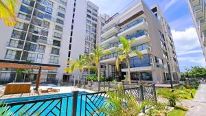an apartment building with a swimming pool and palm trees at Habitación Suite Cerca al Mar - Santa Marta in Santa Marta