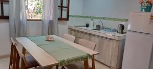 eine Küche mit einem Tisch und einem weißen Kühlschrank in der Unterkunft Complejo Los Azahares in Presidencia Roque Sáenz Peña + 3 Fotos