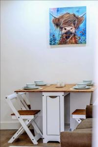 a table with a painting of a cow on the wall at Modern Comforts – 4 Bedroom Home for Work & Play in Swansea