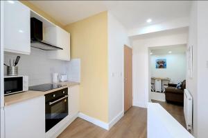 a kitchen with white cabinets and a counter top at Modern Comforts – 4 Bedroom Home for Work & Play in Swansea +12 photos