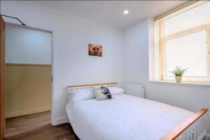 a bedroom with a large white bed with a window at Modern Comforts – 4 Bedroom Home for Work & Play in Swansea