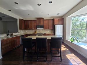 a kitchen with wooden cabinets and a kitchen island with chairs at Renovated 4BR 6 Bed 3 and a half Bath Near DFW Airport in Lewisville