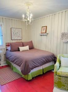 - une chambre avec un lit, un lustre et une chaise dans l'établissement Long Lake Getaway-Hot Tub-Pet Friendly-Near Alpena, à Alpena