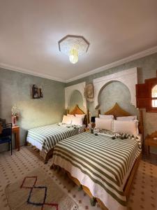 une chambre avec deux lits avec des draps rayés dans l'établissement Riad Jenan Adam, à Marrakech