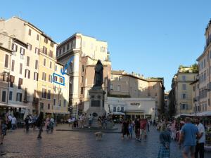 eine Gruppe von Menschen, die mit einer Statue durch eine Straße gehen in der Unterkunft The column of Campo de' Fiori in Rom
