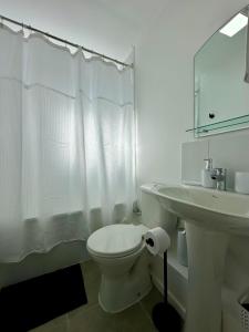 a white bathroom with a toilet and a sink at Latitud Guesthouse in Puerto Montt